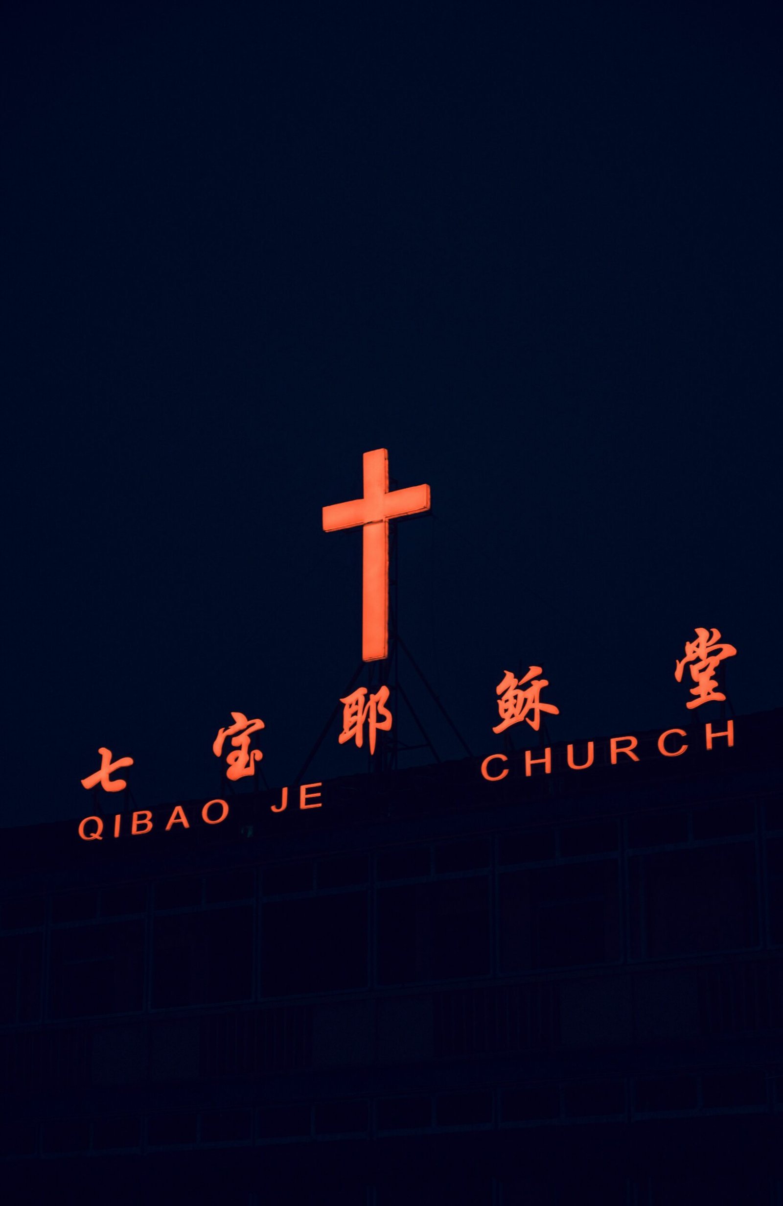 A lit up cross on top of a building